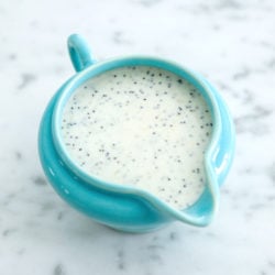 lemon poppyseed dressing in a turquoise blue pitcher on a marble background