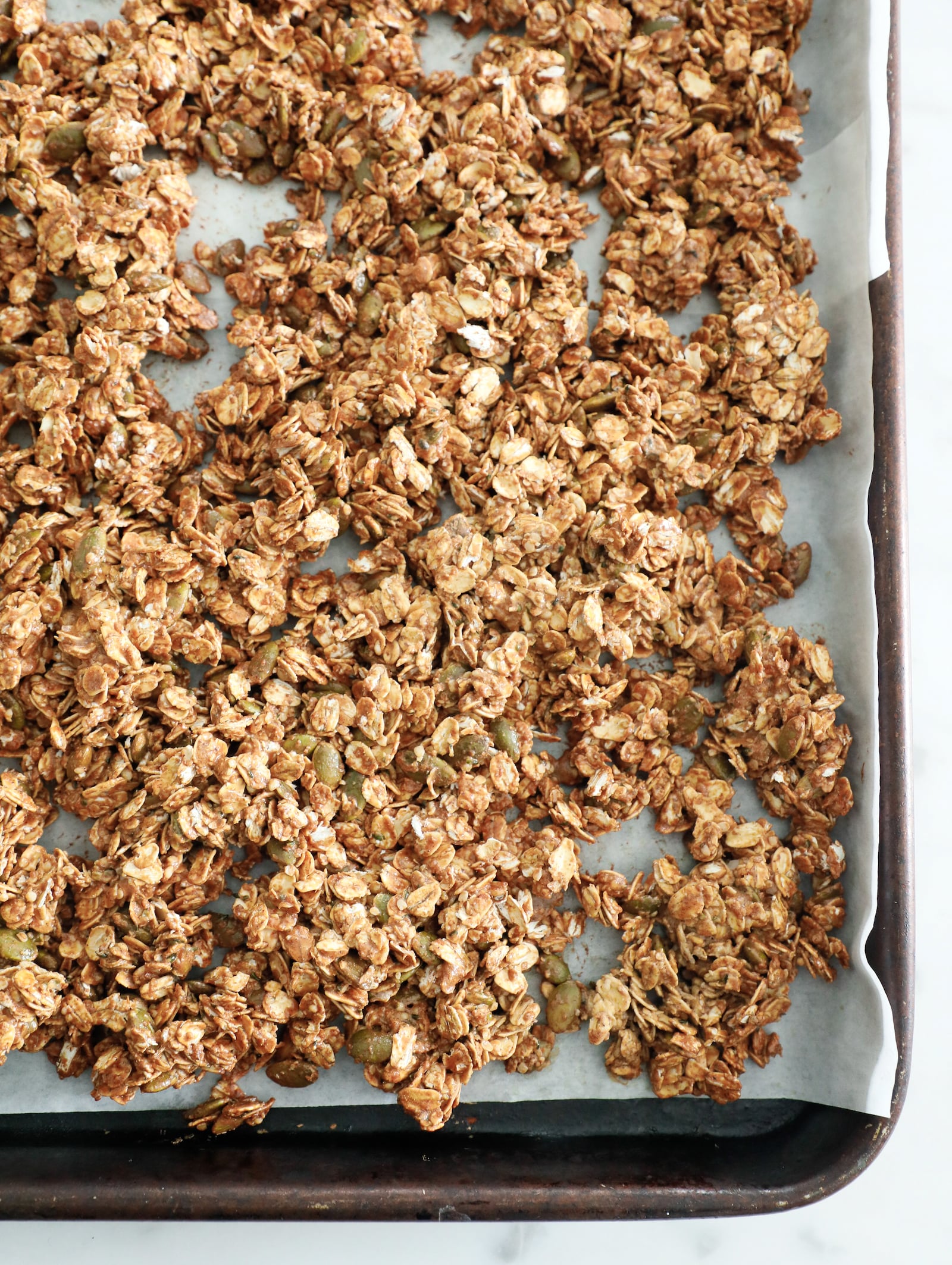 high protein granola after being baked on a sheet pan lined with parchment paper.