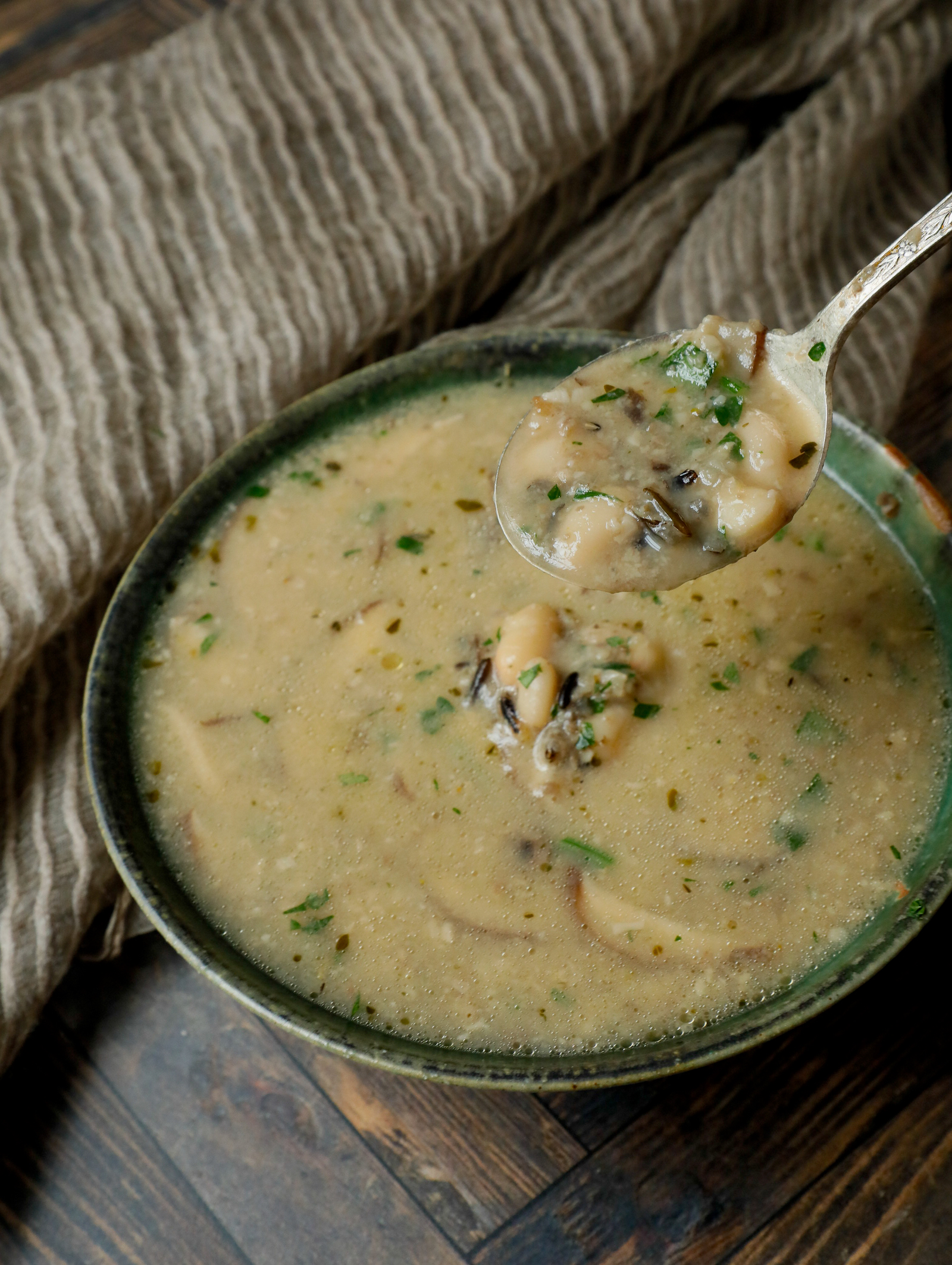 Spoonful of mushroom soup with rice, beans and parsley.