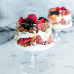 A high protein yogurt parfait in a crystal goblet on a marble background