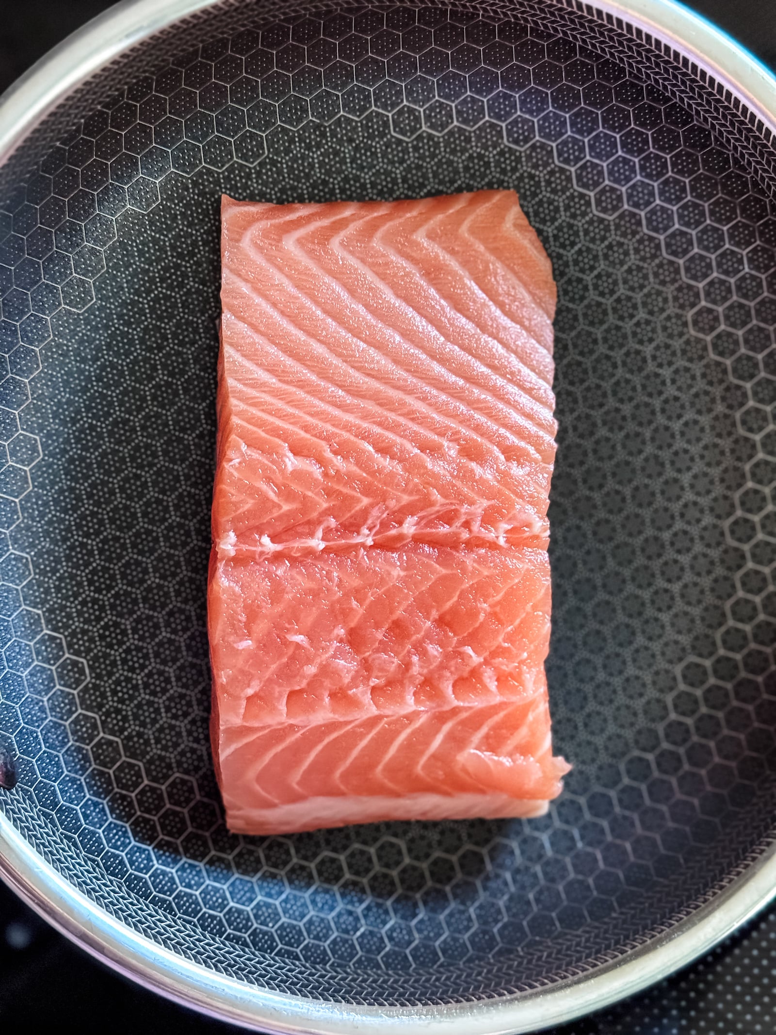 raw salmon filet in a hex clad saute pan ready for cooking.
