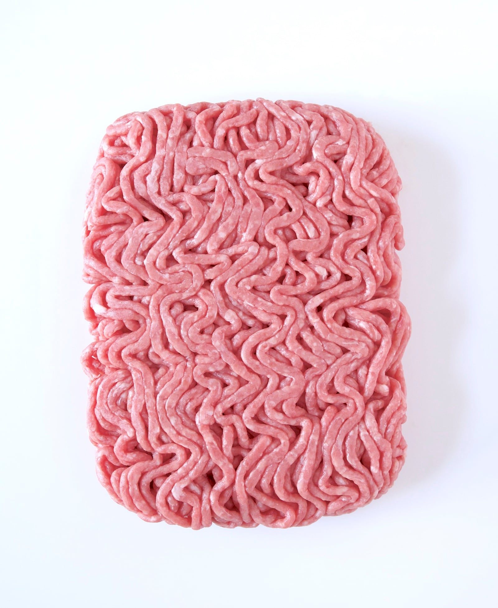 1 pound of a rectangle of raw ground beef on a white background shot from the top.