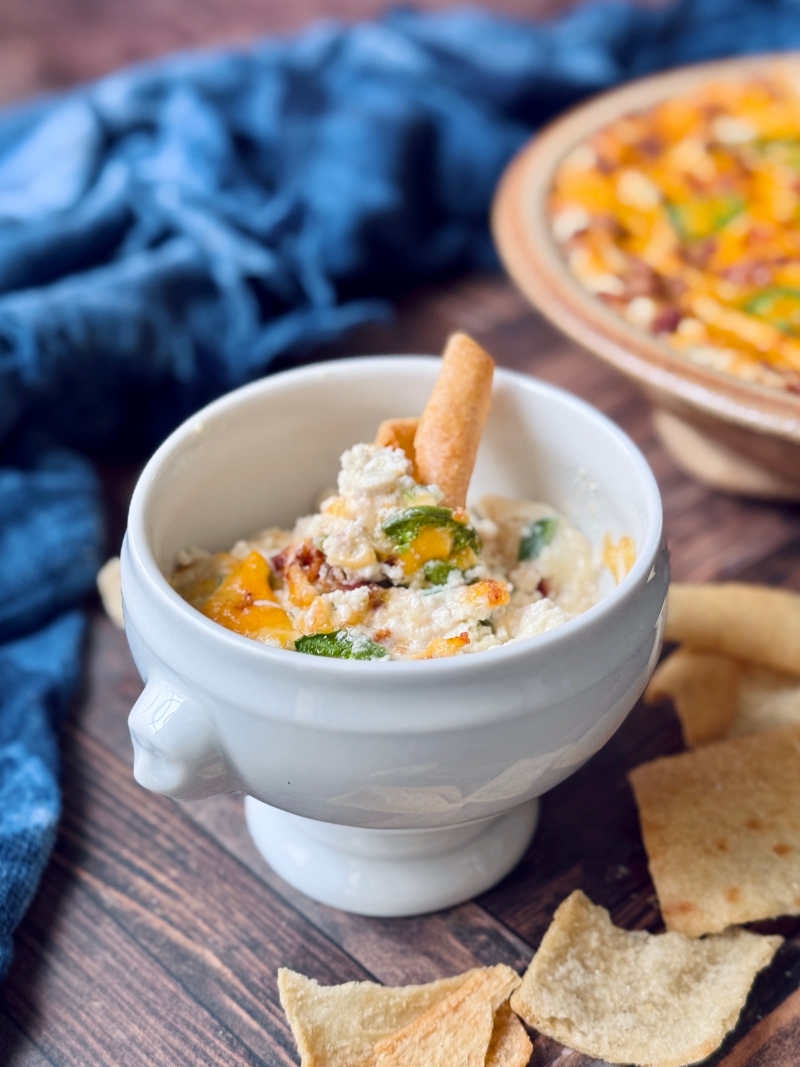 high protein jalapeno popper dip in a white bowl with a pita chip on top