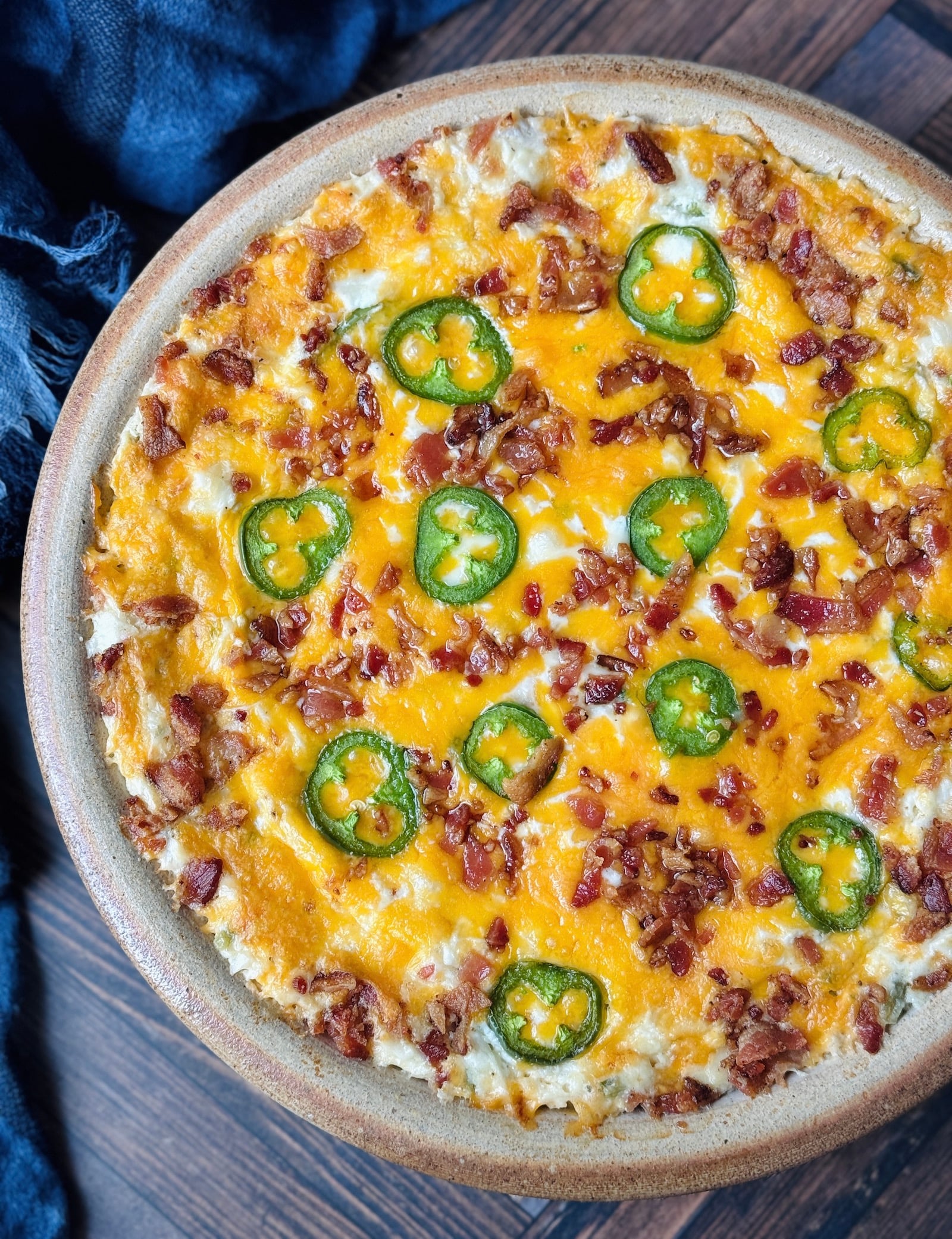 high protein jalapeno popper dip in a pottery pie plate shot from above with a blue cloth napkin in the background