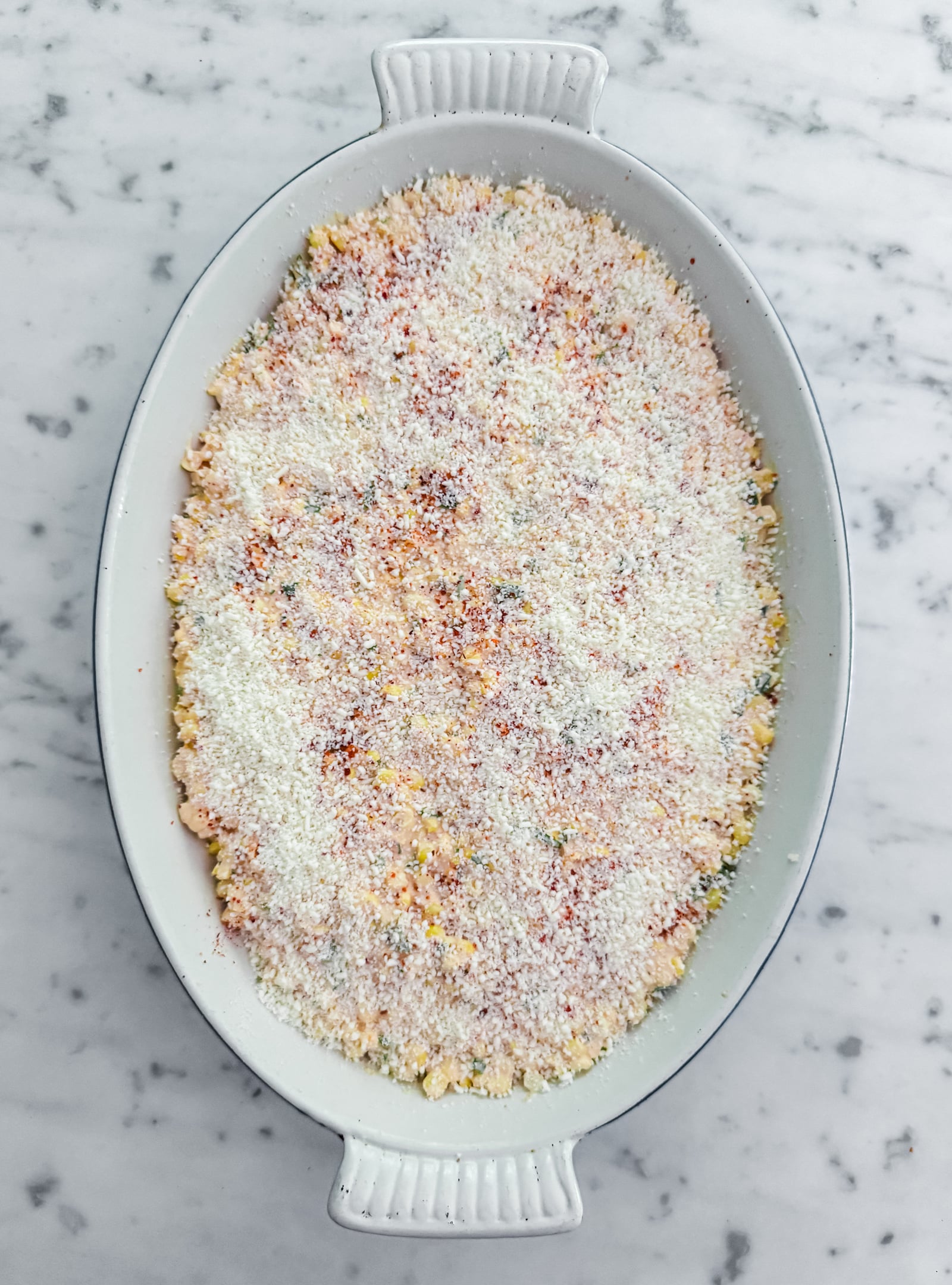 High protein street corn casserole in an oval baking dish, before going into the oven.