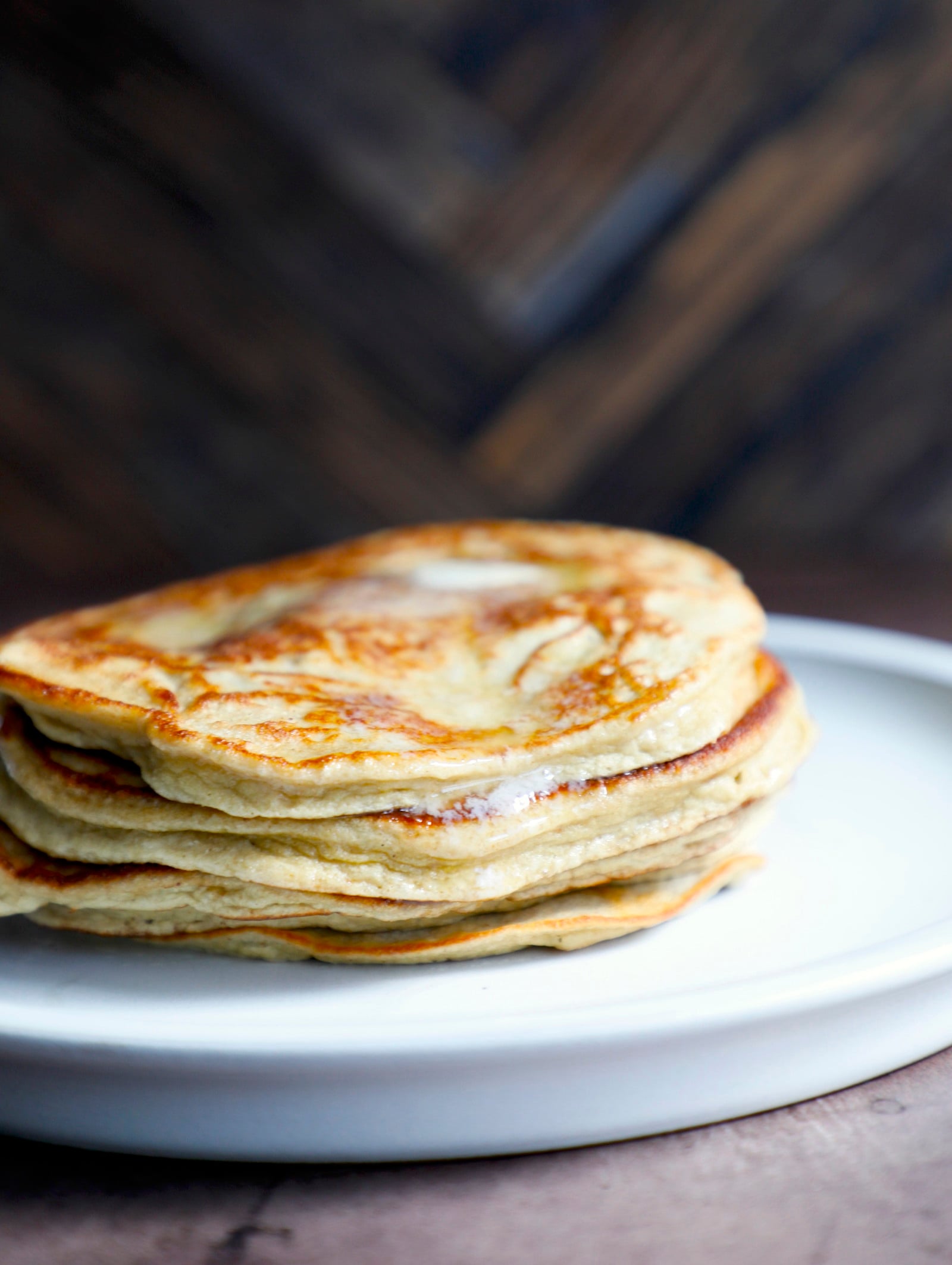 A stack of fluffy keto pancakes with melted butter dripping over the side.
