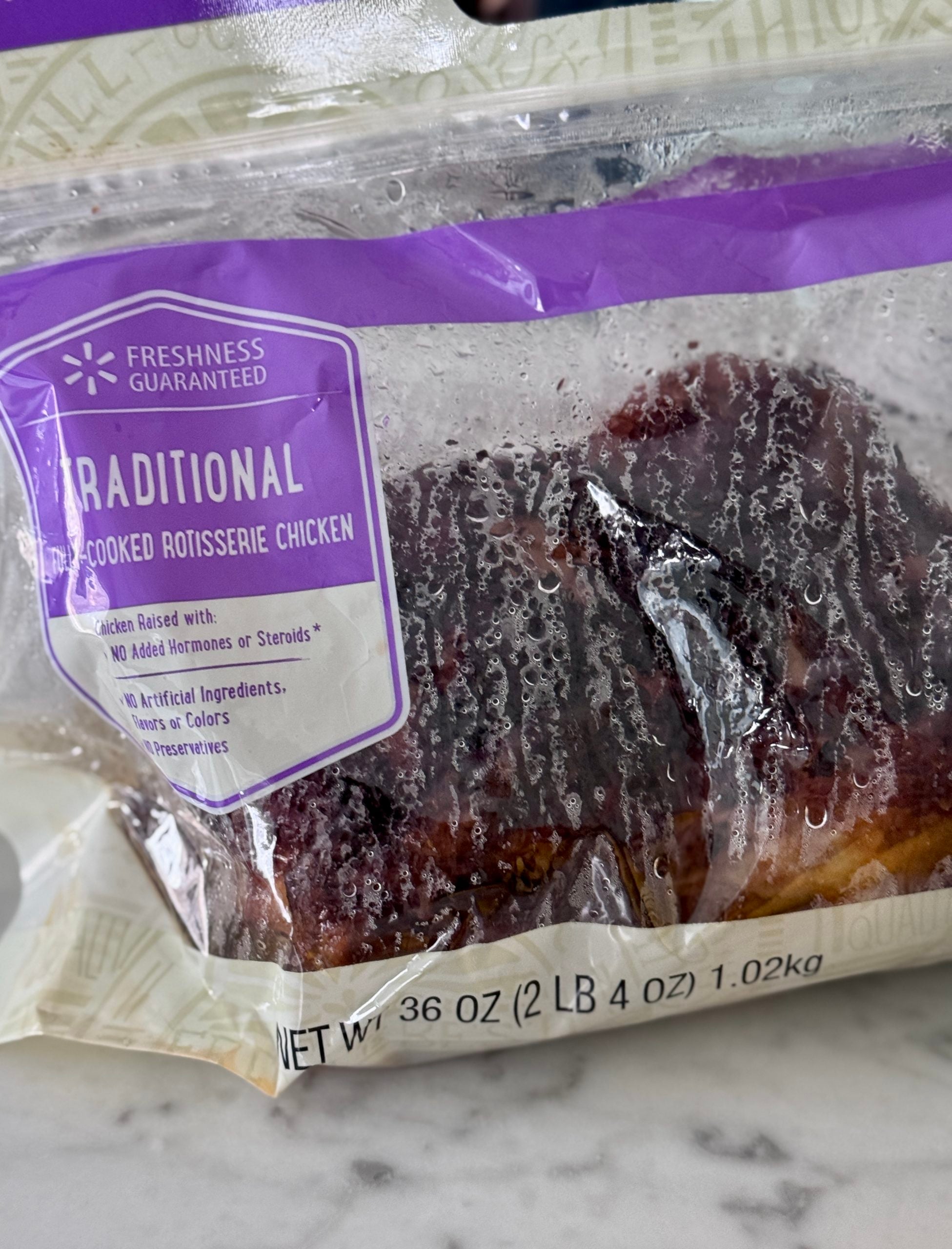 Walmart rotisserie chicken in a labeled bag, fresh from the store and on a marble counter