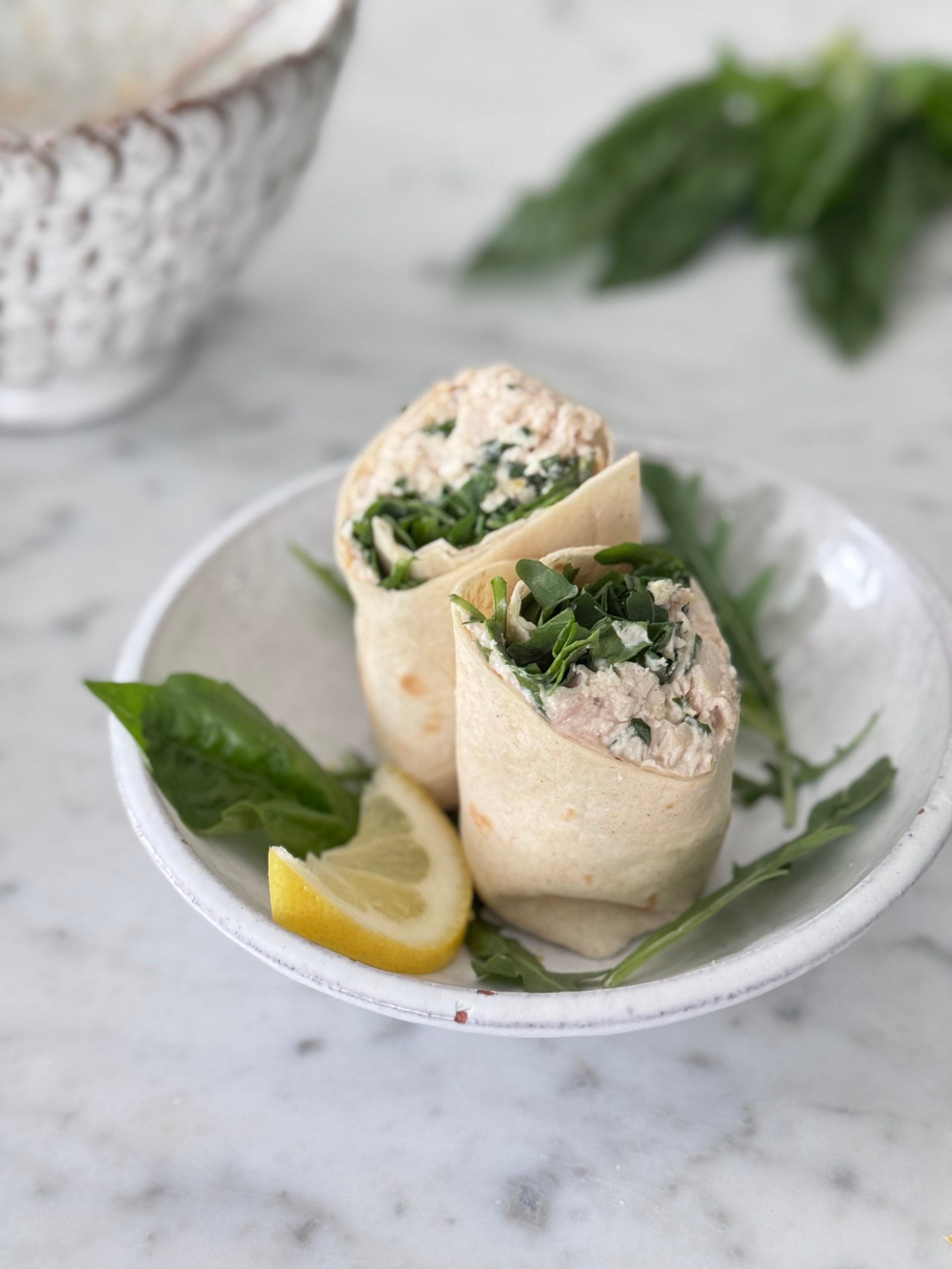 Keto chicken salad wrap in a low carb tortilla with arugula, lemon, and basil