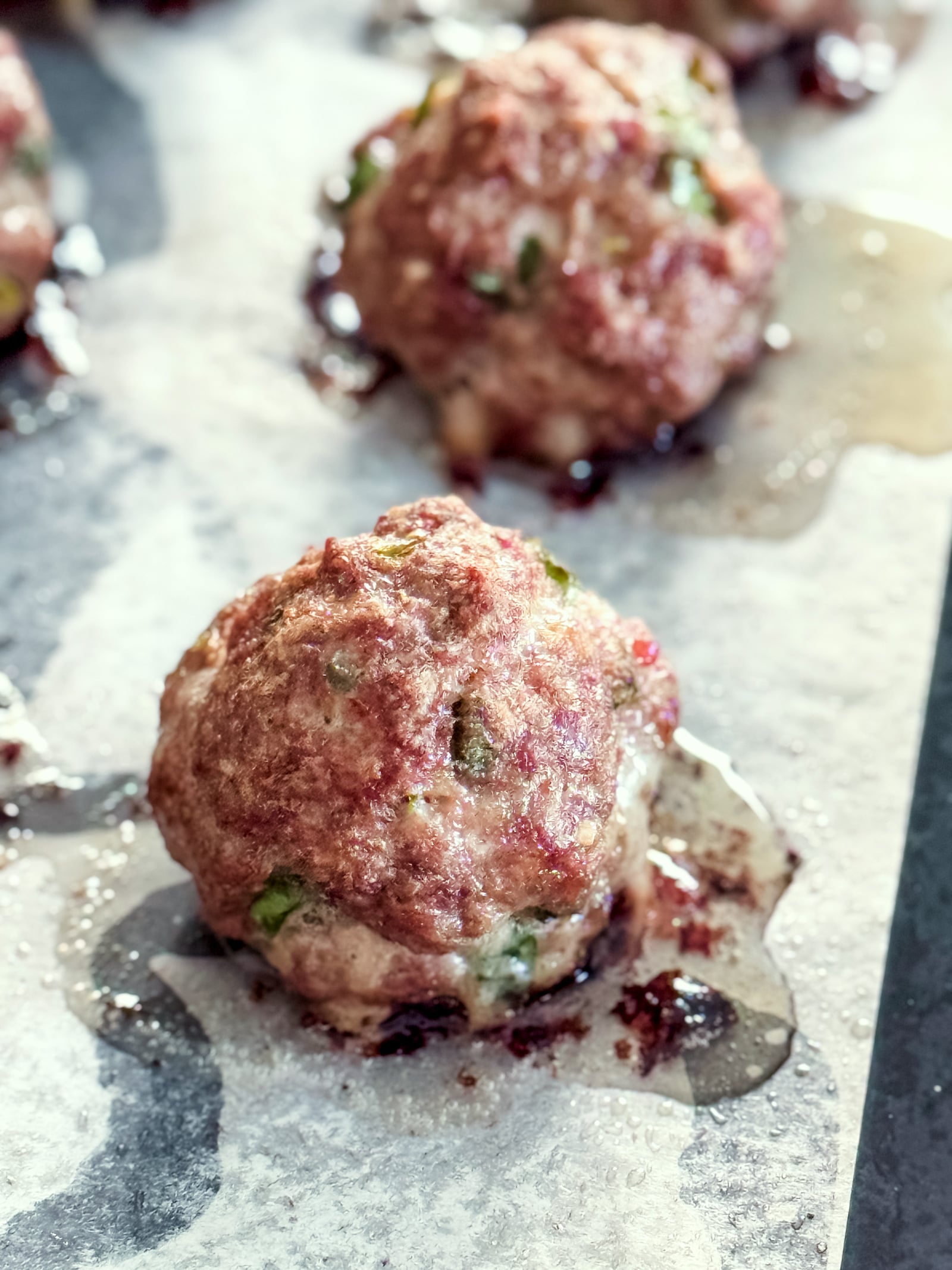 Korean bulgogi meatballs on a parchment lined baking sheet after being baked until golden brown.