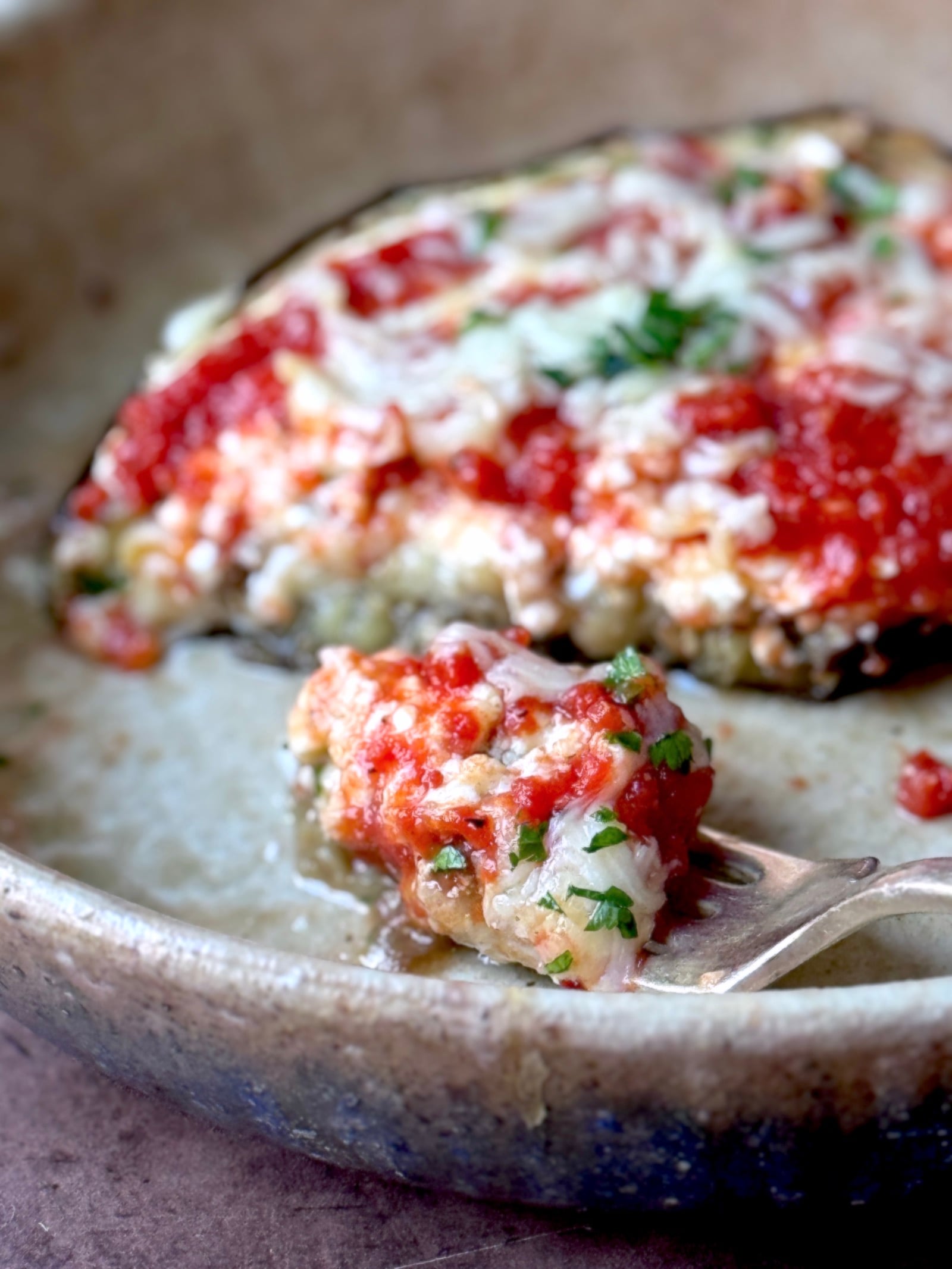 A forkful of high protein low carb eggplant parmesan with marinara, cottage cheese, and mozzarella cheese on top.