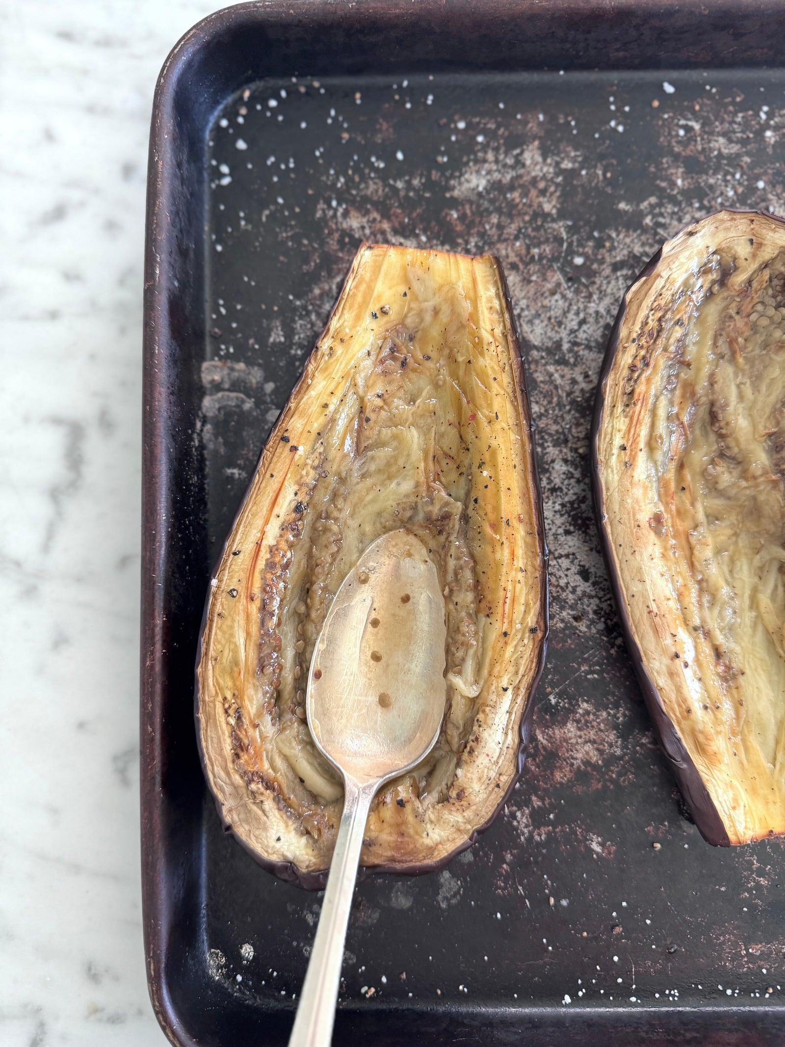 Use a spoon to press down the roasted eggplant in the center to create a boat for the stuffed eggplant filling.